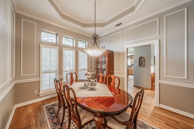 Dining room featuring light hardwood / wood-style floors, crown molding, and a tray ceiling