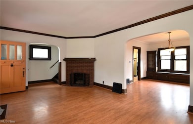 Living room with ornamental molding, light hardwood floors, and a fireplace