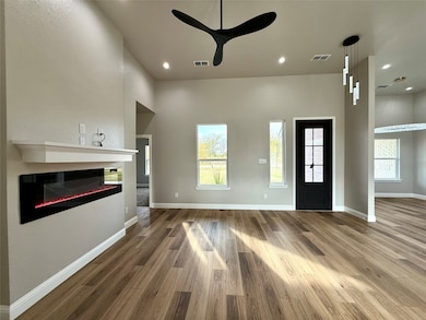 Unfurnished living room with a glass covered fireplace, wood finished floors, recessed lighting, and ceiling fan