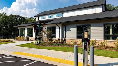 View of front of house with uncovered parking, board and batten siding, a shingled roof, and fence