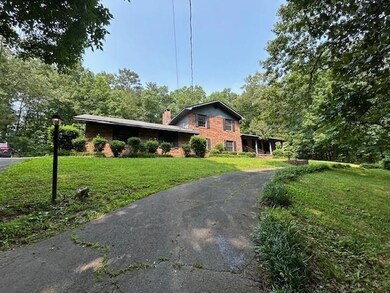 View of front of house with a front circle asphalt driveway, a chimney, and brick siding