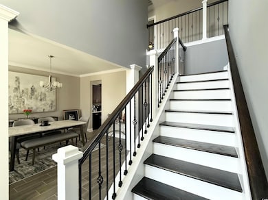 Stairway with ornamental molding, wood finished floors, a chandelier, and a towering ceiling