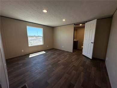 Unfurnished bedroom with dark wood finished floors, a textured ceiling, recessed lighting, and connected bathroom