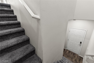 Stairway with wood finished floors and a textured wall