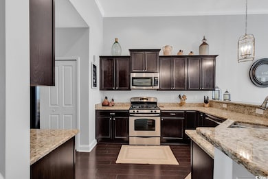 Kitchen with light stone counters, hanging light f