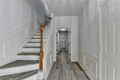 Stairway with a decorative wall, wainscoting, wood finished floors, and crown molding