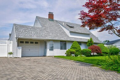 View of front facade featuring a garage, decorative driveway, a chimney, and roof with shingles