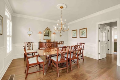 Dining space featuring a chandelier, plenty of natural light, ornamental molding, wood finished floors
