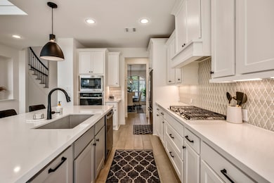 You will love the details of this kitchen! It features a large single basin sink and modern back faucet, black cabinet hardware, quartz counters, under cabinet lighting, and a large kitchen island with contrasting cabinets.