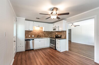 Kitchen with white cabinetry, crown molding, dark 