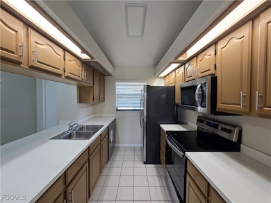 Kitchen featuring stainless steel appliances, light tile patterned floors, and light countertops