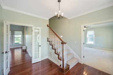 Staircase featuring crown molding, wood-type flooring, french doors, a chandelier, and a ceiling fan