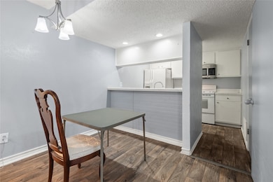 Dining space with dark wood-type flooring, a textured ceiling, and a chandelier