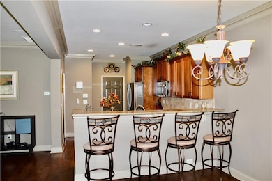 Kitchen with ornamental molding, brown cabinetry, a peninsula, a kitchen breakfast bar, and tasteful backsplash