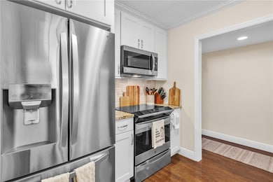 Gorgeous renovated kitchen w/ special pantry door, SS appliances (counter depth fridge/slide-in range), granite counters, crown molding, tumbled marble backsplash, under counter lighting & engineered wood floors!