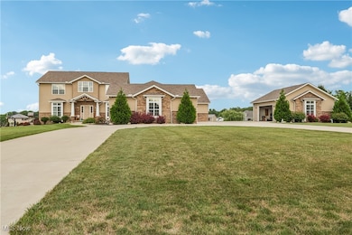 View of front of property with stone siding, curved driveway, and a front yard