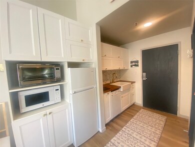 Kitchen featuring white cabinetry, white appliances, light wood-style floors, and backsplash