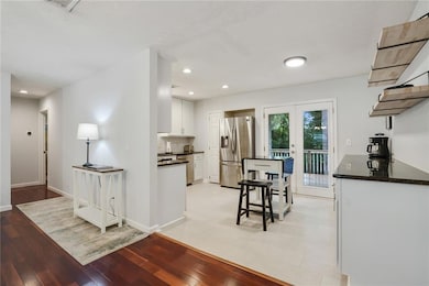 Kitchen with stainless steel appliances, dark countertops, white cabinetry, light wood finished floors, and recessed lighting
