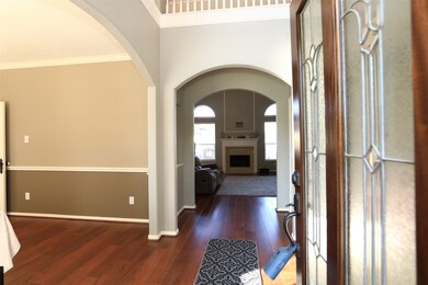 View into home, with luxurious laminate flooring, high ceilings and arches leading to rooms.