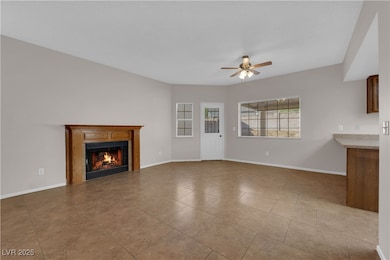 Unfurnished living room featuring a lit fireplace, a ceiling fan, and light tile patterned flooring