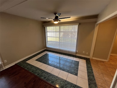 Unfurnished room featuring light tile patterned flooring, inlaid floor details, and a ceiling fan