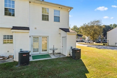 Back of property with central AC and a lawn