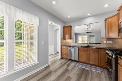 Kitchen with brown cabinets, stainless steel appliances, dark wood finished floors, tasteful backsplash, and dark stone counters