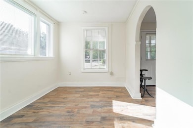 Spare room featuring healthy amount of natural light, arched walkways, and wood finished floors