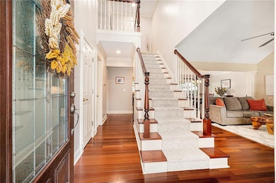 Entrance foyer with a towering ceiling, dark wood finished floors, crown molding, stairway, and a ceiling fan