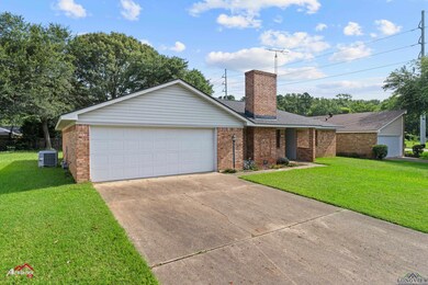 Single story home featuring brick siding, concrete driveway, a chimney, and a front yard