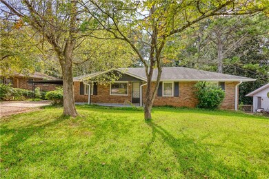 Ranch-style house with a front yard, brick siding, driveway, and a carport