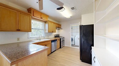 Kitchen with stainless steel appliances, separate washer and dryer, light wood finished floors, a peninsula, and under cabinet range hood