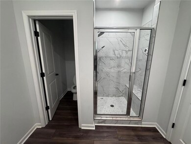 Bathroom featuring dark wood-type flooring and a marble finish shower