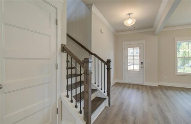 Entryway with light wood-style floors, crown molding, stairway, and baseboards
