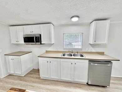 Kitchen with appliances with stainless steel finishes, white cabinetry, light wood-type flooring, light countertops, and a textured ceiling