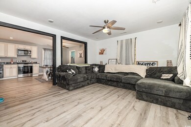 Living room featuring ceiling fan and light wood-t
