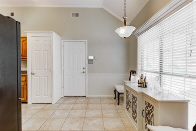 Entryway featuring a wainscoted wall, crown molding, vaulted ceiling, and light tile patterned flooring