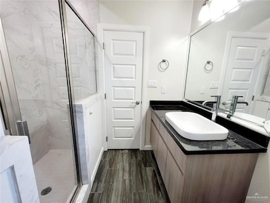 Bathroom featuring baseboards, vanity, a marble finish shower, and wood finished floors