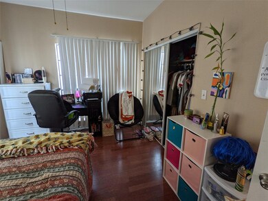 Bedroom with dark wood-style flooring and an offi