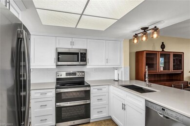 Kitchen with appliances with stainless steel finishes, a sink, white cabinetry, and light countertops