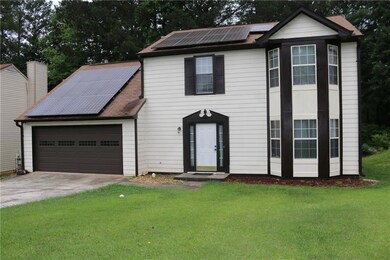 View of front of home featuring roof mounted solar panels, driveway, a garage, a front lawn, and a shingled roof