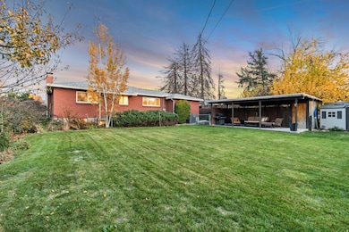 Back of house at dusk with a yard, a chimney, brick siding, a patio area, and outdoor lounge area