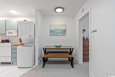 Dining area with stacked washer and clothes dryer, a textured ceiling, and baseboards