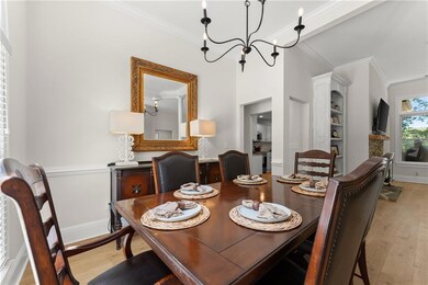 Dining space with ornamental molding, light wood-style floors, a chandelier, and baseboards