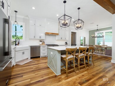 Kitchen featuring quartz, stainless steel appliances premium range hood, oversized island, hanging light fixtures, and LVP flooring
