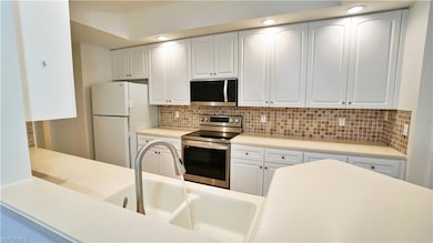 Kitchen with light countertops, a sink, tasteful backsplash, stainless steel appliances, and white cabinets