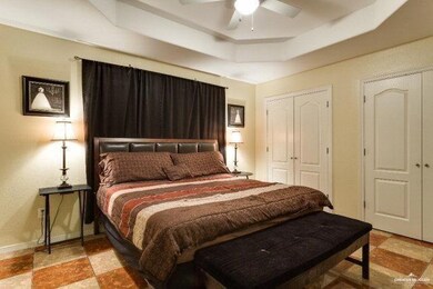 Bedroom with baseboards, a tray ceiling, ceiling fan, and a closet