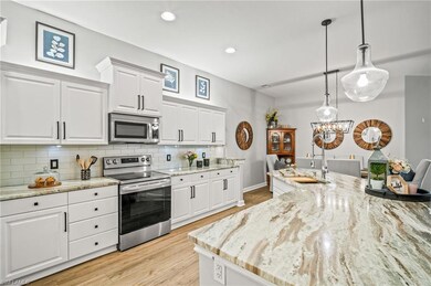 Kitchen featuring appliances with stainless steel finishes, tasteful backsplash, white cabinets, light wood finished floors, and recessed lighting
