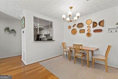 Dining room featuring an inviting chandelier, ornamental molding, wood finished floors, and a textured ceiling