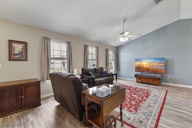 Living room with vaulted ceiling, ceiling fan, and